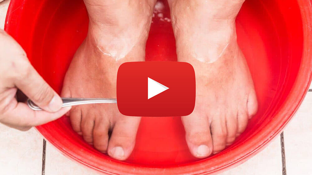 Feet soaking in a red basin filled with water, with a hand holding a spoon