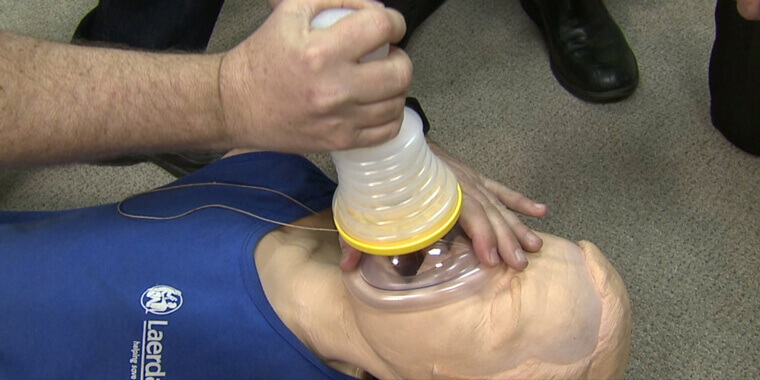 Person demonstrating an anti-choking device on a CPR dummy