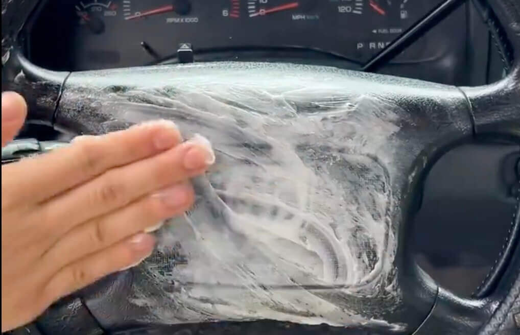 Hand applying Vaseline to a car dashboard